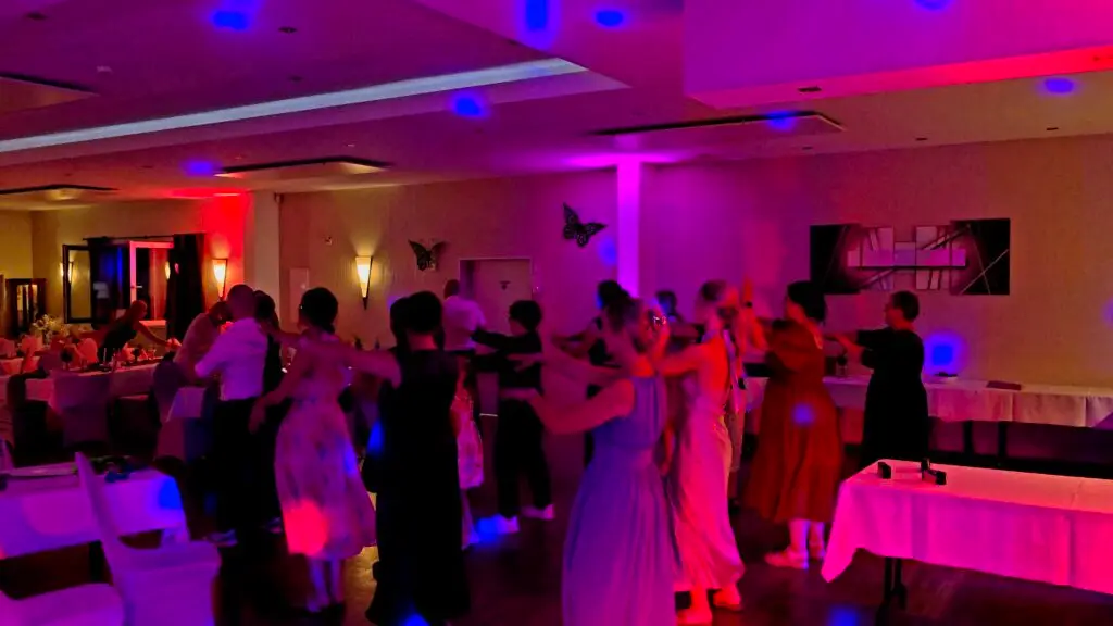 Fröhliche Hochzeitsgäste beim Macarena Tanz auf der Tanzfläche mit professioneller Festbeleuchtung von einem Hochzeits DJ im Saarland.