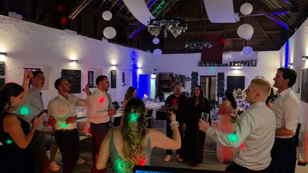 Ausgelassene Partygäste bei einer Hochzeit in einer Scheune mit stimmungsvoller Partybeleuchtung von einem Hochzeits DJ im Saarland.
