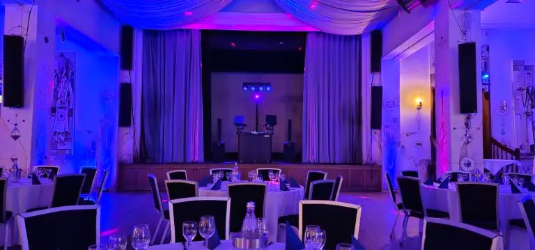 Stimmungsvoll beleuchteter Festsaal mit DJ-Equipment auf der Bühne für eine Hochzeit im Saarland.