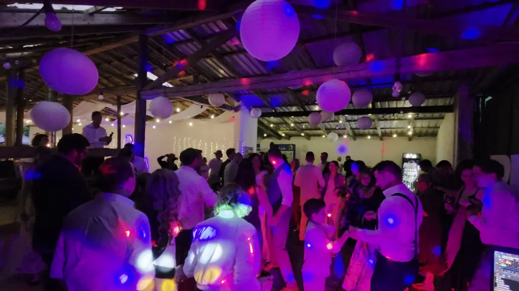 Volle Tanzfläche unter weißen Papierlampions bei einer Scheunenhochzeit mit stimmungsvoller Partybeleuchtung von einem Hochzeits DJ im Saarland.