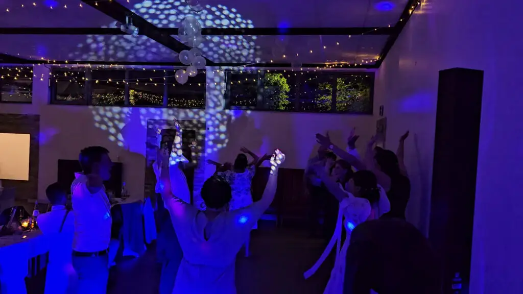 Tanzende Hochzeitsgäste im Saarland unter bewegten Lichteffekten und Lichterketten an der Decke.